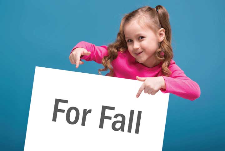 girl holding sign that says, "For Fall"