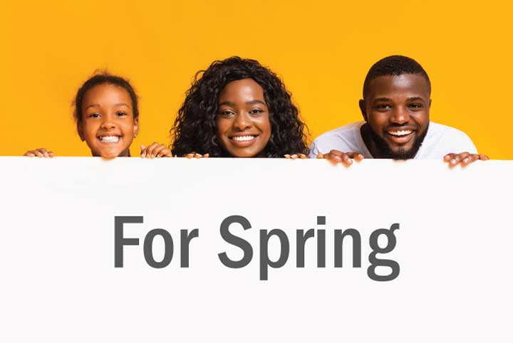 African-American girl, woman, and man look over sign that reads, "For Spring"