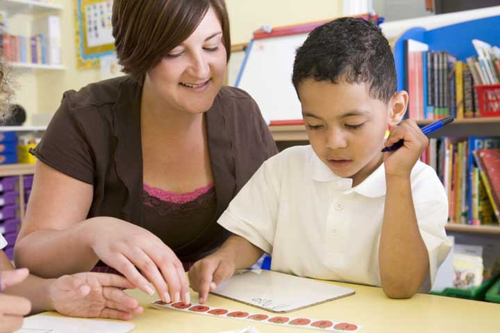 Primary school teacher helping boy with math