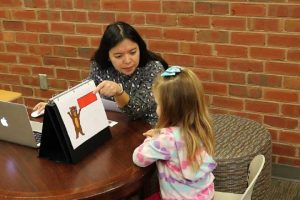 A woman administering the early mathematics assessment system to a young kindergarten girl.