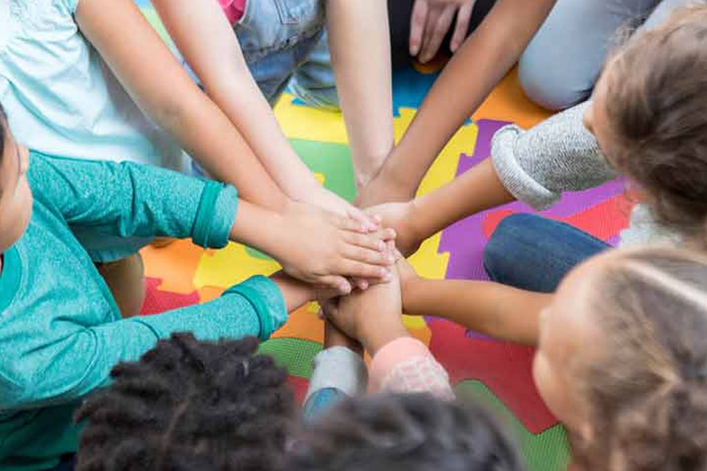 Children putting hands together in group cheer
