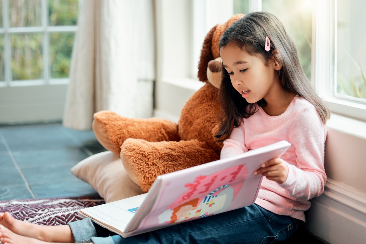 Girl reading to stuffed animal
