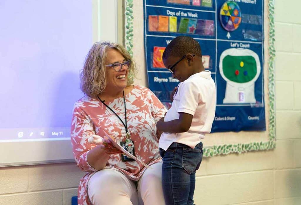 Child and educator smile at each other