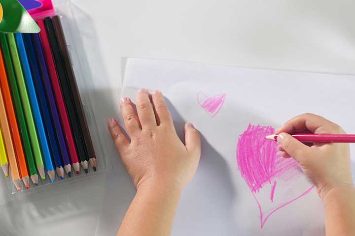 A close-ups of pencils and a child's hands drawing a heart