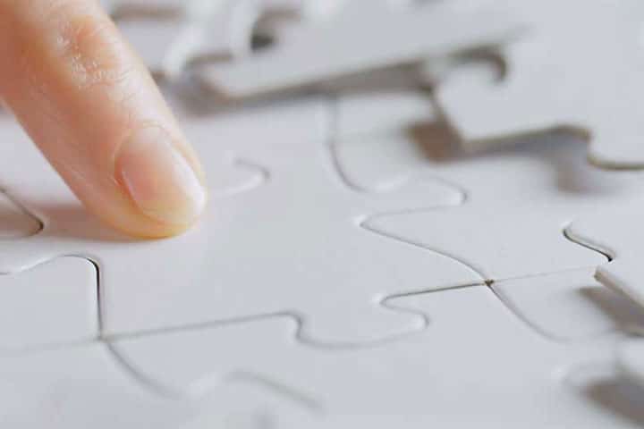 A finger pointing at puzzle pieces that fit together